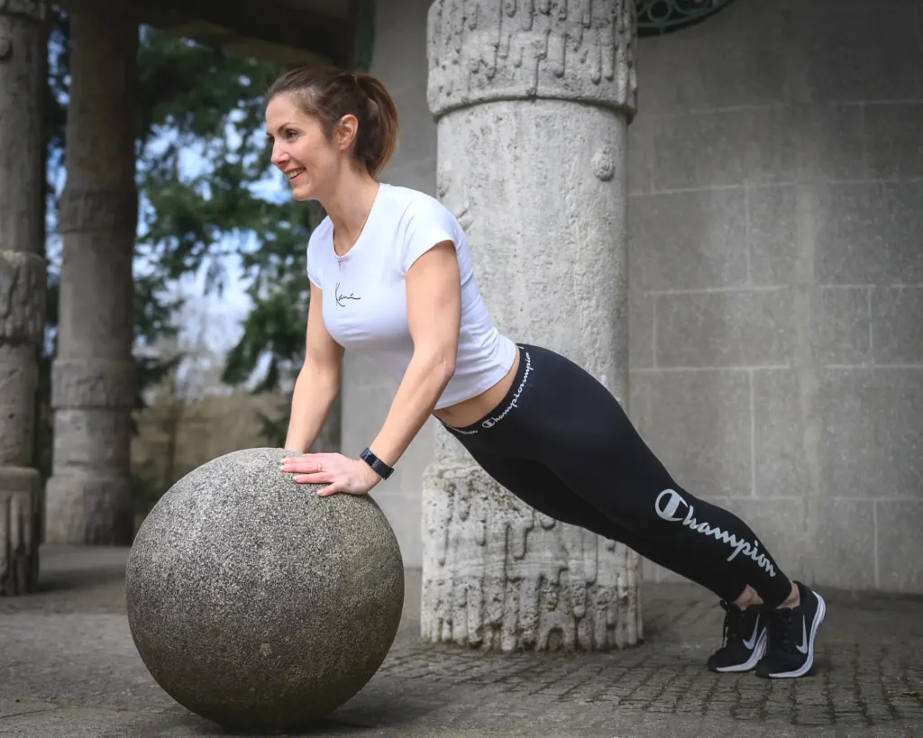 Elena März 2021-48 a woman doing push ups on a large stone ball, Frau mach Liegestütze
